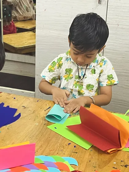 This young boy is focused on folding paper for his dragon. The accordion fold is a fundamental paper craft technique that creates movement and dimension.