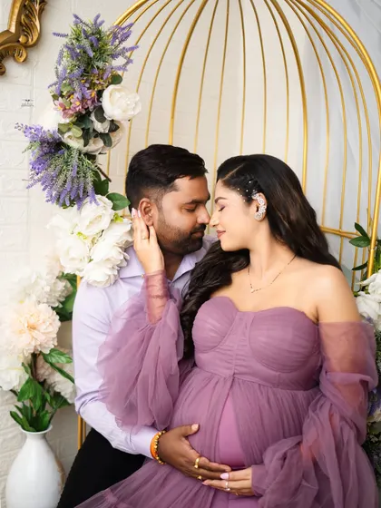 An intimate and romantic pose, with the couple sharing a gentle touch. The soft lighting and floral details make this a truly dreamy maternity photo.