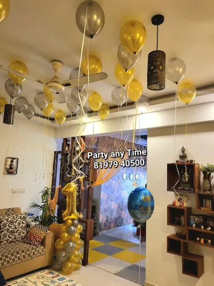Gold and silver helium balloons filling the living room for a first birthday party.