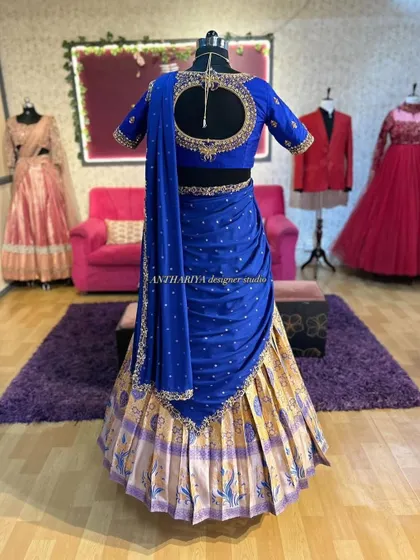 This royal blue and gold Langa Voni is displayed on a mannequin to show its full design. Notice the intricate cutout back and detailed embroidery on the blouse.