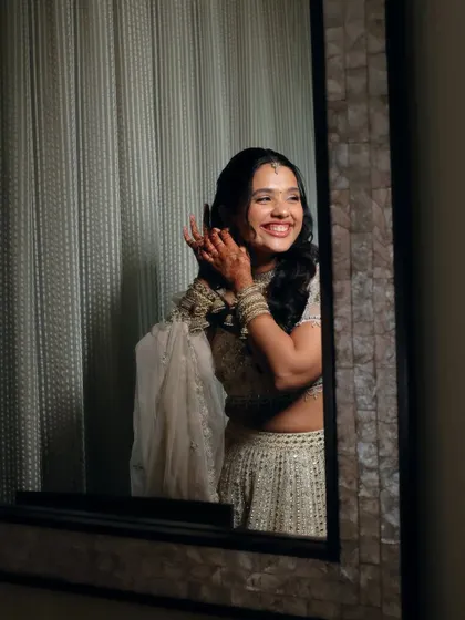 A mirror selfie moment. The bride is checking her final look, and her joyful smile shows she loves the soft, romantic makeup and hair.