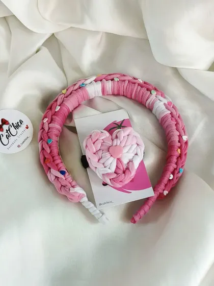 A lovely pink braided headband paired with a matching heart-shaped hair tie.