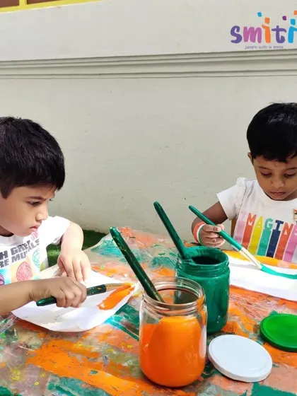 Two boys concentrate on painting the saffron and green stripes on their flags. This art project is a hands-on lesson in patriotism and creativity.