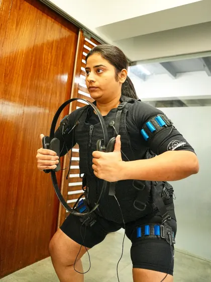 This client performs a squat with a resistance ring, showing how EMS can be combined with other tools for a comprehensive workout.