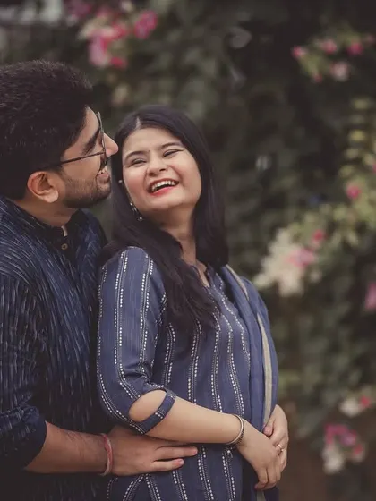 A sweet, smiling portrait of a couple during their pre-wedding session, set against a soft, natural background.