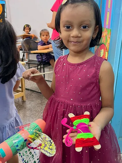 A proud artist holds up her finished yarn butterfly. These simple, tactile crafts are perfect for our summer camp sessions with younger children.