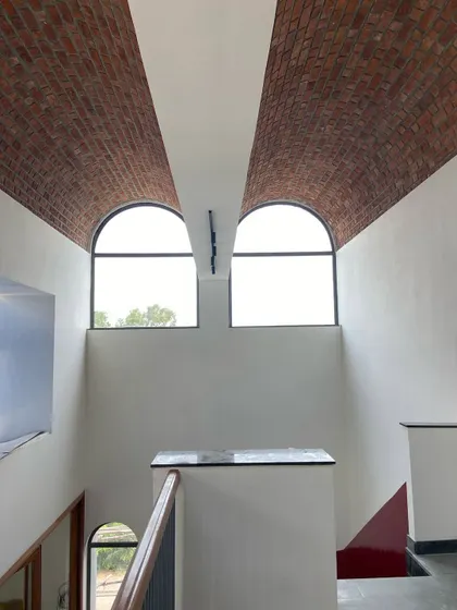 A symmetrical view of the twin arched windows, which create a sense of classical order within the modern, rustic space.