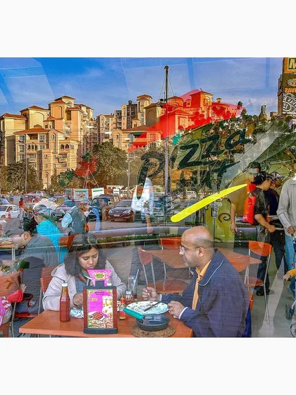 This reflection captures a busy urban scene, layering a family meal inside a restaurant with the city life outside. It is a complex visual story of modern life, with multiple narratives coexisting in one frame.