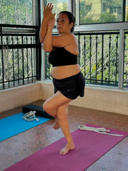 A student holds Garudasana (Eagle Pose), demonstrating focus and balance. This pose strengthens the ankles and calves while stretching the thighs, hips, and shoulders.
