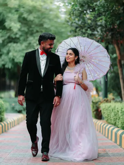 A candid shot of the couple walking together. The flowy nature of the pink maternity gown makes it look beautiful in motion, ideal for dynamic photoshoot poses.