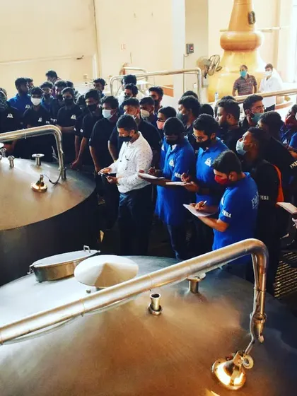 Students on a distillery tour, taking notes as they learn about the large-scale production of spirits.