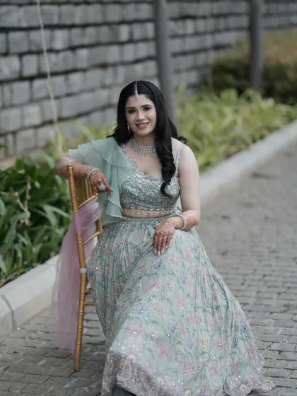 A full-length portrait showcasing her beautiful pastel green lehenga. The makeup is kept soft and elegant to balance the intricate floral details of her outfit.