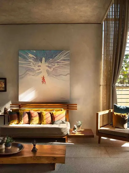 This living room is a celebration of contemporary Indian design. We used a neutral palette of concrete-finished walls and floors as a canvas for vibrant, traditional Indian textiles on the cushions and a bold piece of modern art, creating a space that feels both global and local.
