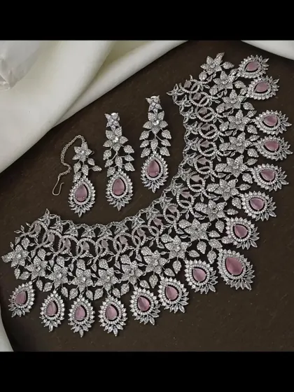 This intricate CZ stone necklace set with pink stones is a beautiful choice for a reception. The floral and leaf motifs give it a delicate look.