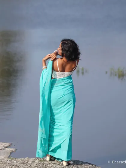 Another beautiful shot from the back, this portrait emphasizes the elegant drape of the saree and the peaceful waterside setting.