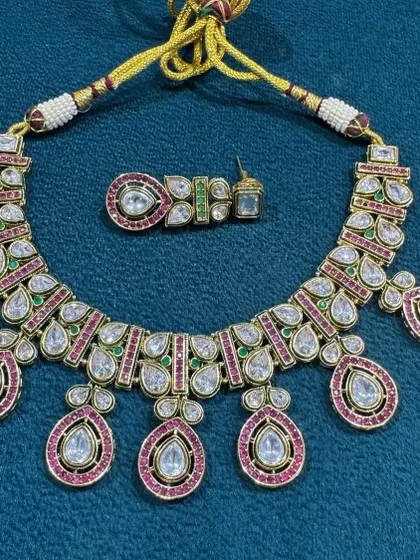 A classic and elegant kundan necklace set that you can never go wrong with. The combination of large uncut polki style stones with ruby and green accents makes it a timeless piece for weddings and festivals.