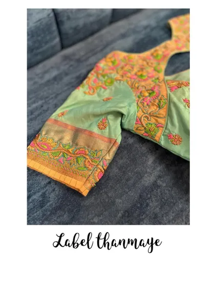 A close-up of the sleeve of the pastel green blouse, showing the colorful threadwork.
