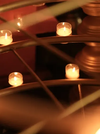 The soft glow of tea-light candles placed in a decorative holder, creating a warm and intimate ambiance for an evening ceremony.