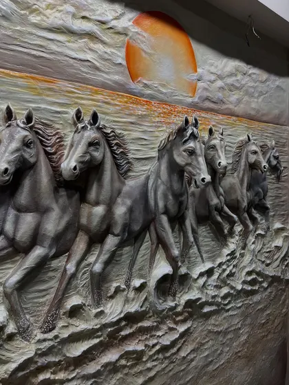 A close-up of the dark 7 horses mural, where the horses are finished in a metallic grey against a textured sea and a striking orange sun.