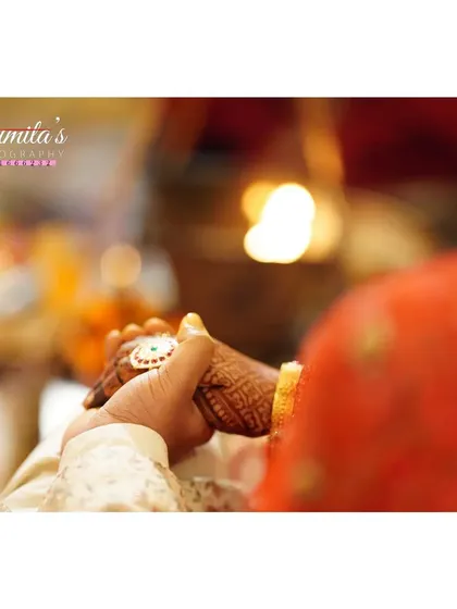 A close-up of the couple holding hands during the ceremony. The focus on their intertwined hands, with the sacred fire in the background, symbolizes their new bond.