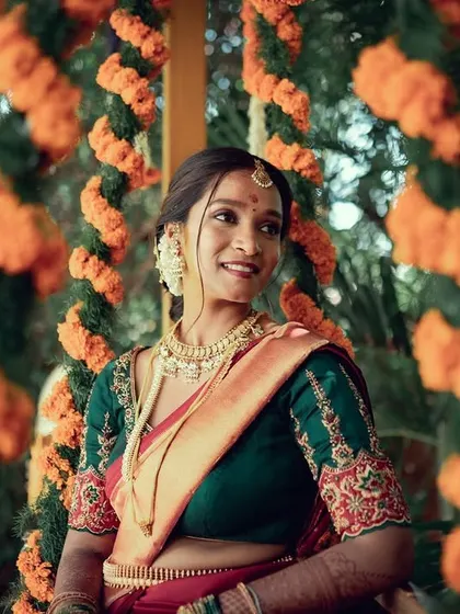 A candid shot of a bride enjoying her wedding festivities, with a soft smile and a backdrop of festive marigold decorations.