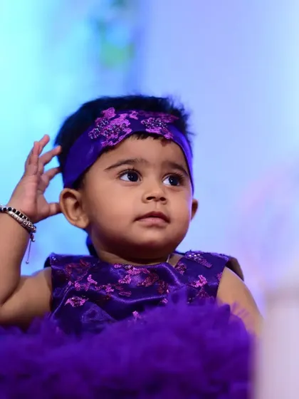 A close-up on the details of the purple party dress. The bodice features a subtle pattern with sequins, and the custom-made headband is adorned with matching embellishments for a fully coordinated look.