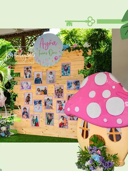 A personalized photo memory board from Ayra's first birthday, surrounded by whimsical props like a giant clock and a mushroom house.