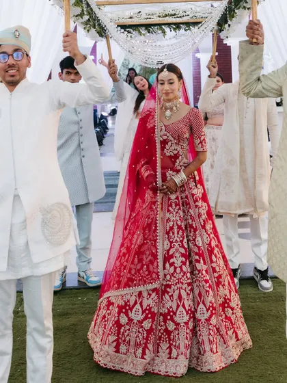 The bride's grand entrance under the phoolon ki chadar. Her makeup is fresh and radiant, making her glow as she walks down the aisle.