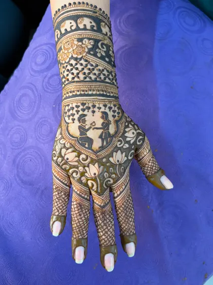 One hand for the bride, one for the groom! This engagement mehendi features a cute couple portrait, with each person on a different palm, surrounded by lotus and elephant motifs.