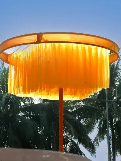 A custom-made fringed lampshade in a brilliant yellow, adding a touch of bespoke design and warm light to the outdoor space.