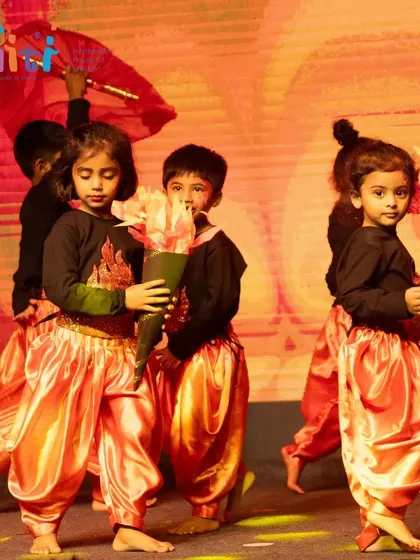 Children in fiery orange costumes perform as Agni (Fire). They hold torches and use red fans to represent the flickering flames.