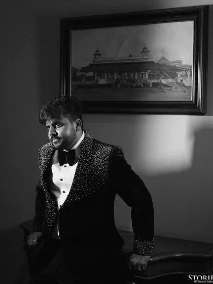 A dapper black and white portrait of the groom in a stylish, embellished tuxedo, exuding confidence and charm.
