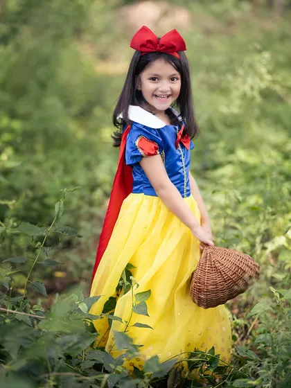 A classic Snow White portrait. The vibrant colors of her dress stand out beautifully against the natural green background.