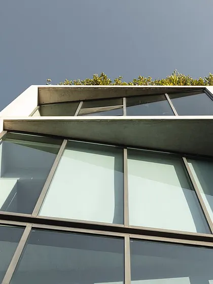 An upward-looking view of our studio's facade. The design features clean lines, a raw concrete finish, and a rooftop garden, reflecting our core architectural principles of materiality, clarity, and integration with nature.