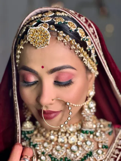 A detailed close-up of the bridal makeup. Notice the flawless base, the rich matte red lip, and the perfectly blended eyeshadow, all coming together for a majestic look.
