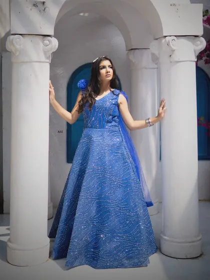 Posed against white columns, the vibrant blue of this sequin gown creates a stunning contrast. It's a perfect dress for a glamorous photoshoot.