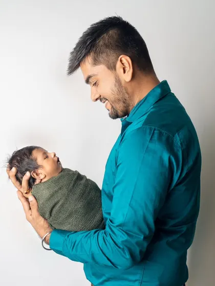 A father's gentle gaze at his sleeping newborn. This simple, clean portrait puts all the focus on the emotion of the moment, creating a timeless image of new fatherhood.