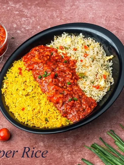 Chopper Rice is a colorful and satisfying meal, featuring a combination of yellow and white fried rice topped with a spicy red chicken gravy, creating three distinct flavors in one dish.