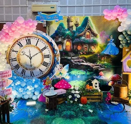 A whimsical 'Onderland' setup with a forest backdrop, a giant clock, and fairy characters.