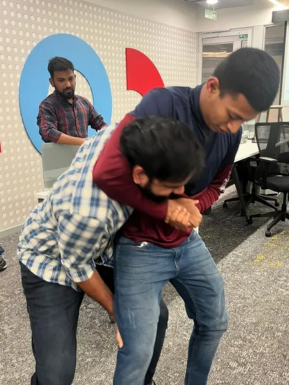 Participants at our Hitachi workshop practicing a technique to escape a bear hug from behind. These are practical skills for real-world scenarios.
