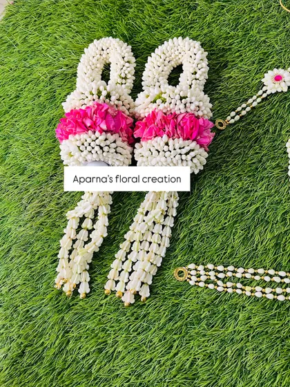 A close-up of fresh floral bajuband made with white buds and accented with pink flowers. These are designed to be worn on the upper arms.