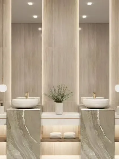 A sophisticated double vanity bathroom with freestanding stone sinks and backlit mirrors. The design uses warm, neutral tones and soft lighting to create a serene, spa-like atmosphere.