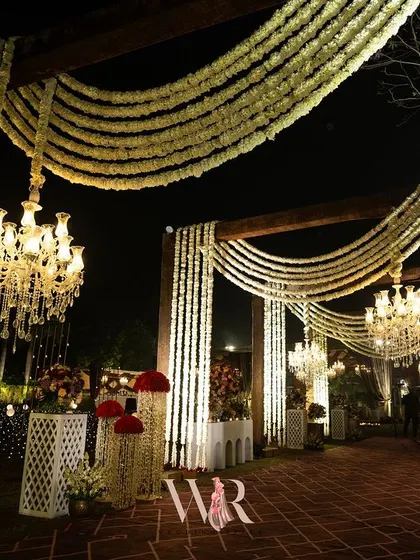 A closer look at the layers of our traditional entrance design. Cascading strings of white flowers create a dense, fragrant canopy, beautifully contrasting with the warm glow of the crystal chandeliers.
