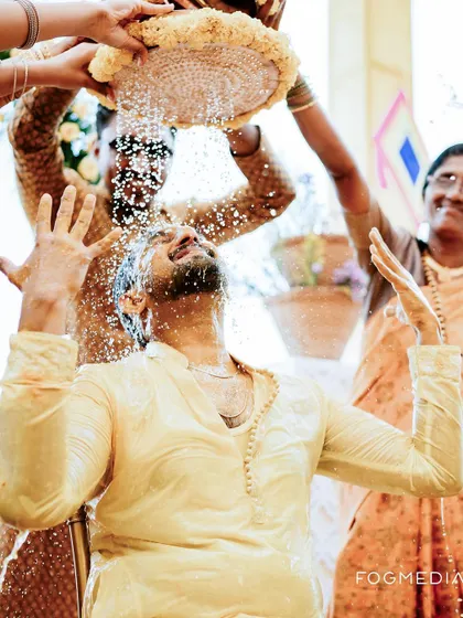 The groom is drenched in a ritualistic shower during his Haldi, a moment of pure celebration.