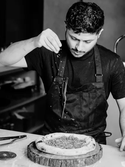 A black and white shot of me at work, adding the finishing touches to a pizza. Every detail matters, and I take pride in making sure each dish is perfect.