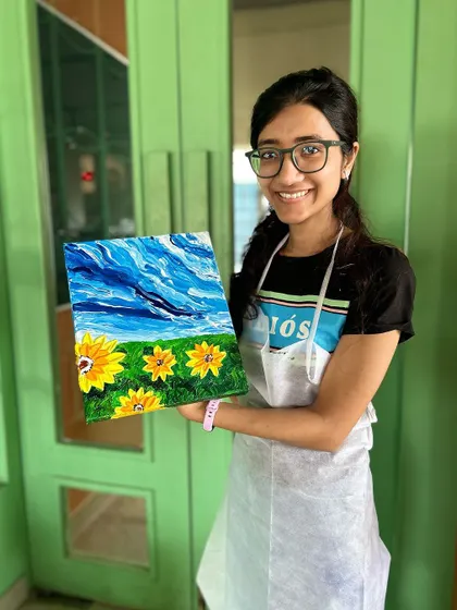 A happy artist with her finished sunflower painting. The vibrant colors and textures make it a cheerful and eye-catching piece.