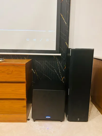 This image shows the front speaker setup, with a powerful subwoofer for deep bass and a floor standing speaker for the main channel. Proper placement is key to achieving a balanced and impactful soundstage for movies and music.