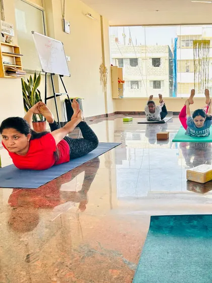 Students holding a strong Dhanurasana (Bow Pose) in our sunlit studio. This pose is excellent for improving posture and strengthening the back muscles.
