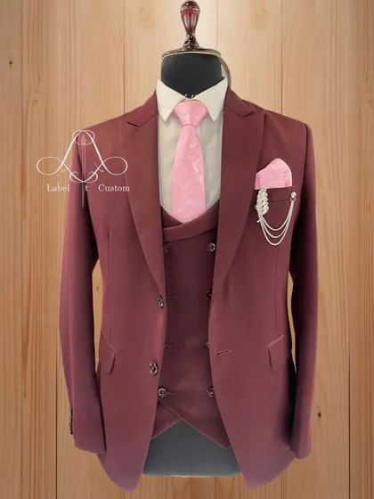A rich maroon three-piece suit paired with a soft pink tie and pocket square. This combination of deep and light tones creates a balanced and elegant look, perfect for a groom or groomsman.