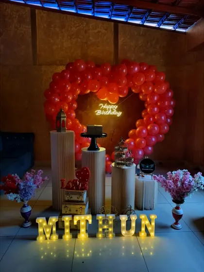 A classic red heart balloon arch with plinths and marquee letters for a birthday surprise.